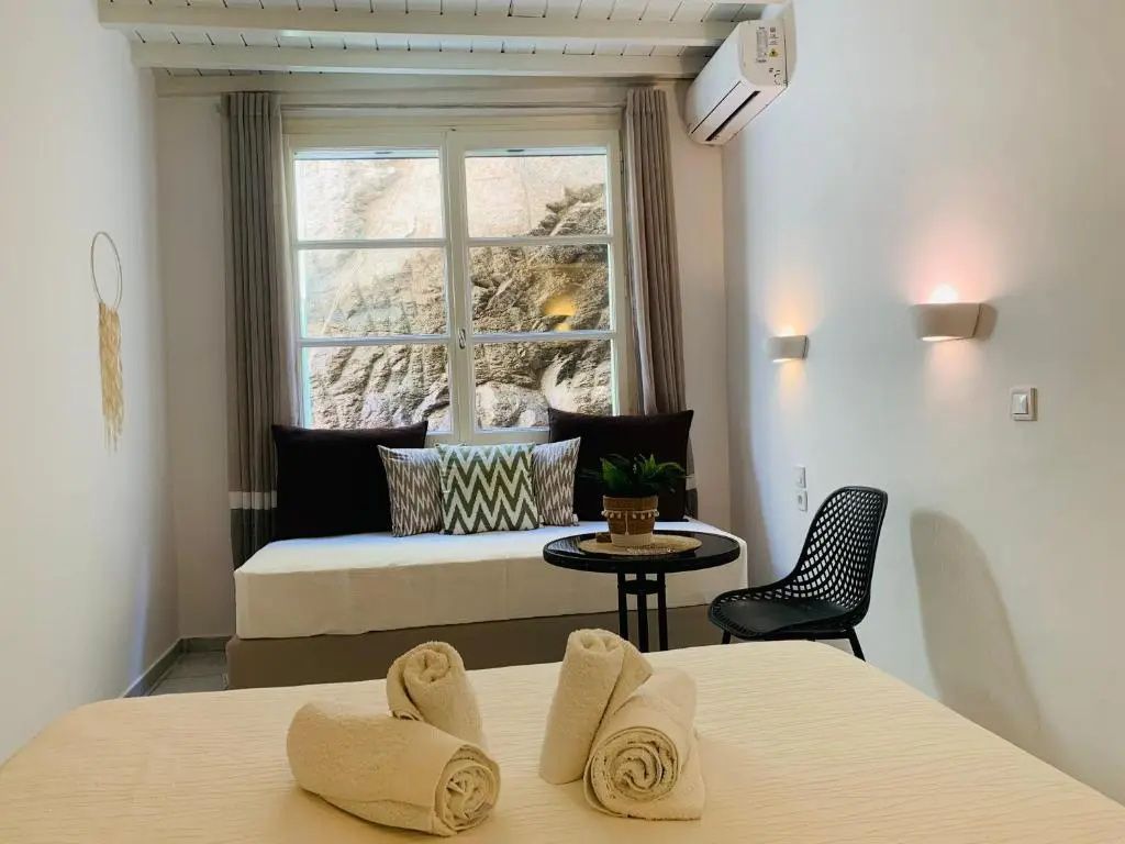 Zimmeransicht mit gerollten Handtüchern auf dem Bett und einer Couch im Hintergrund.