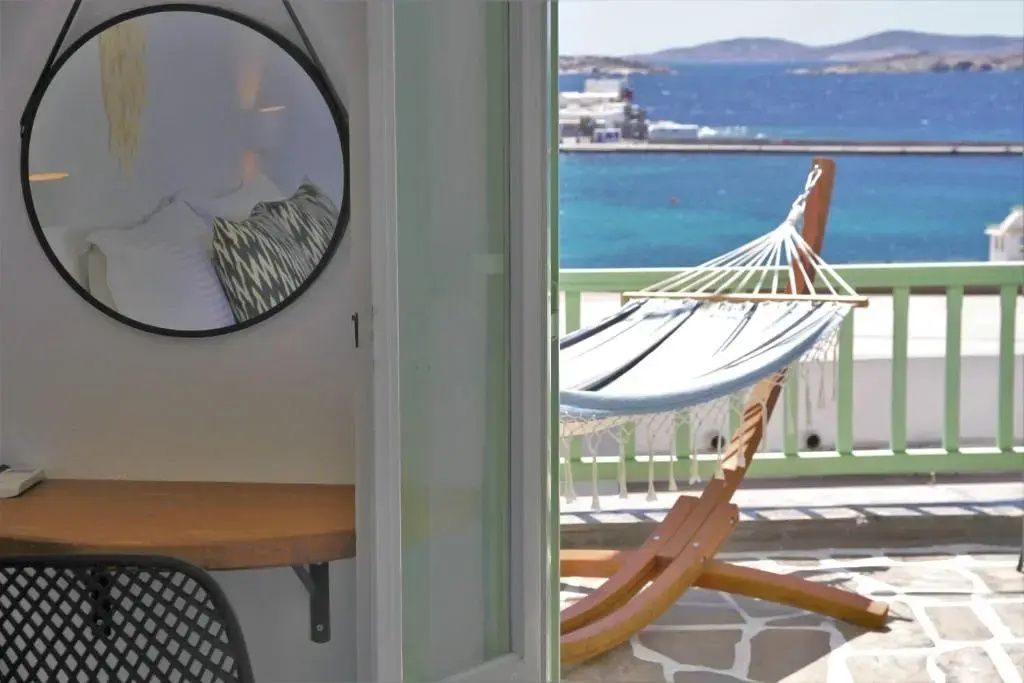 Blick von innen auf den Balkon mit Hängematte und Aussicht auf das blaue Meer.