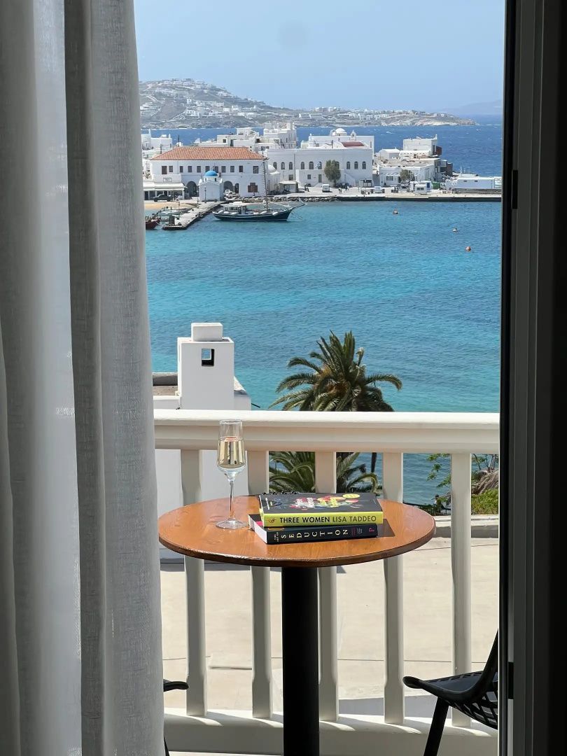 Blick vom Balkon auf das blaue Meer, Palmen und weiße Gebäude.
