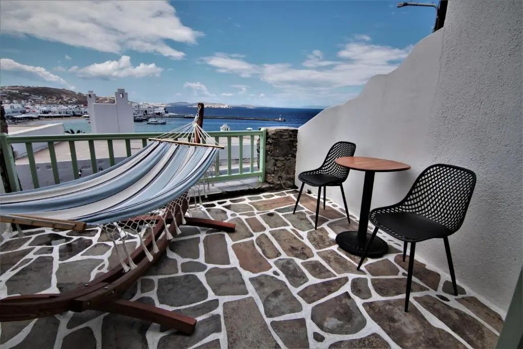 Steinpflaster Terrasse mit einer Hängematte, Tisch, Stühlen und Blick auf den Hafen.