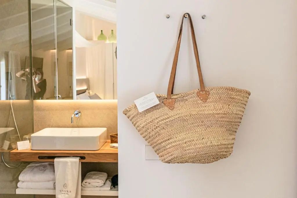 Eine geflochtene Tasche hängt an der Wand neben dem Durchgang zum Badezimmer.