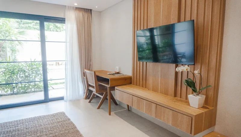 Arbeitsplatz im Zimmer mit Holzschreibtisch, Stuhl und flachem Wandfernseher.
