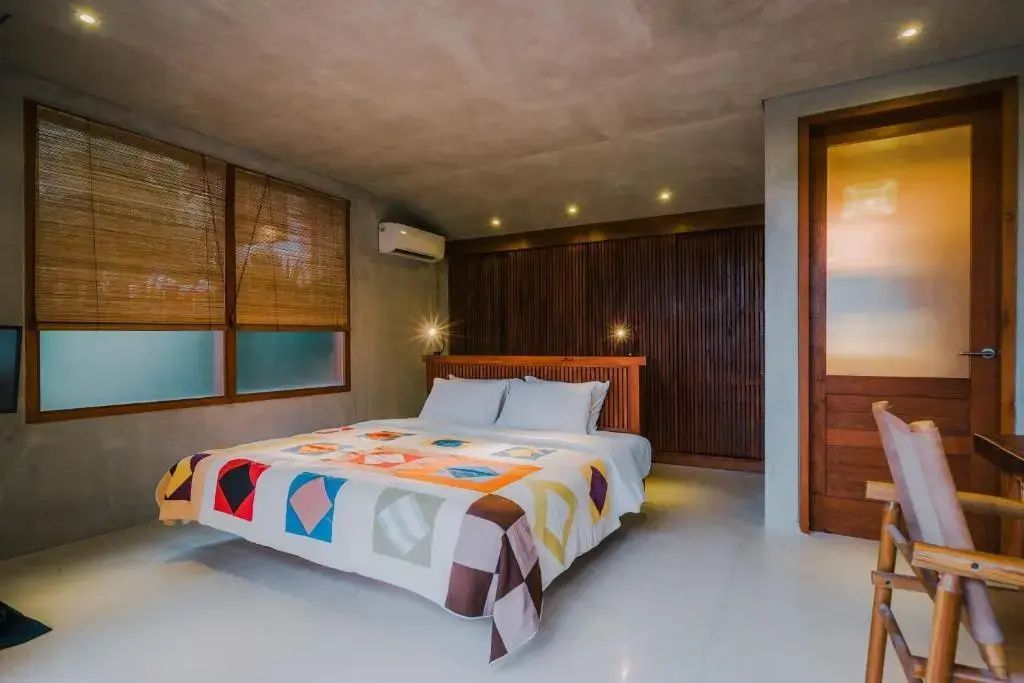 Schlafzimmer mit Holzverkleidung, modernem Doppelbett und bunter Bettdecke.