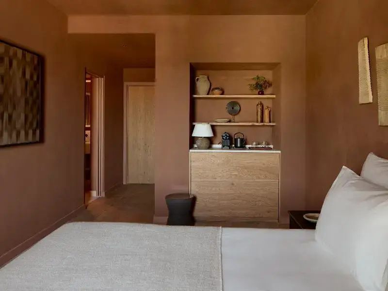 Schlafbereich mit terracottafarbenen Wänden, Holzschrank und integrierter Nische.
