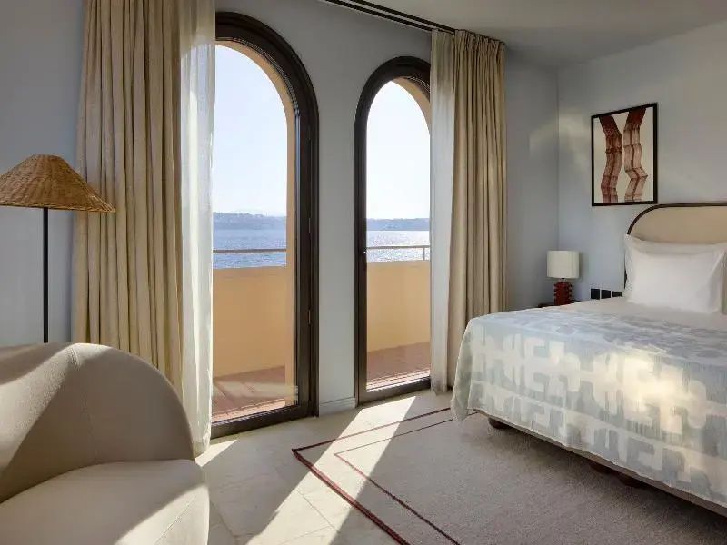 Schlafzimmer mit Rundbogentüren zum Balkon und Blick auf das blaue Meer.