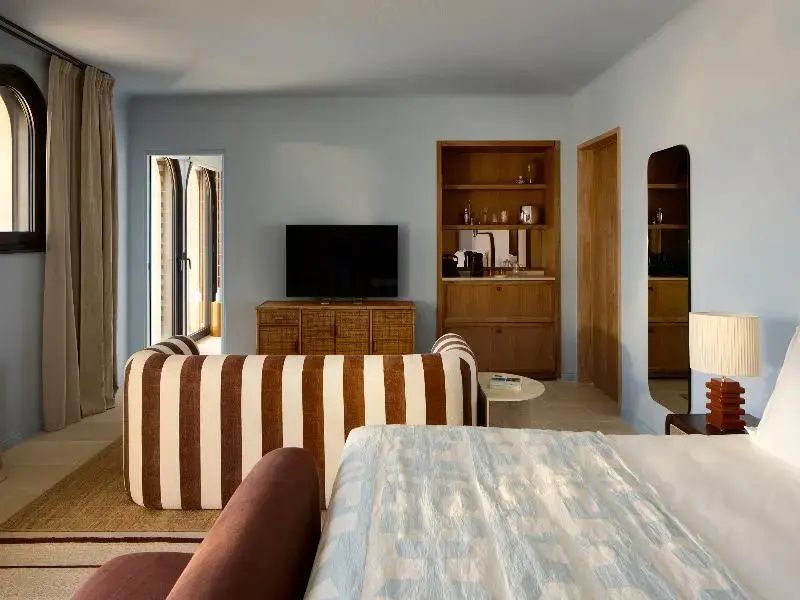 Wohnbereich mit gestreiftem Sofa, Fernseher auf Holzschrank und hellblauen Wänden.