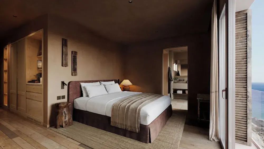 Doppelzimmer mit dunklen Wänden, Holzdekor und Blick in das Badezimmer.