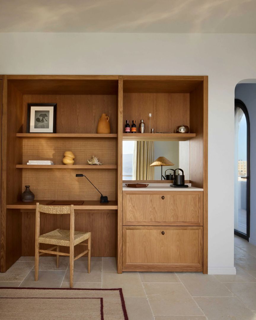 Holzschrankwand mit integriertem Schreibtisch, Holzstuhl, Regalen und Minibar Bereich.