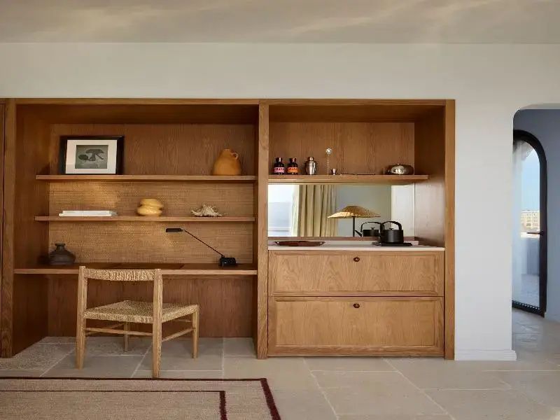 Schrankwand aus Holz mit Schreibtisch, Stuhl und Kaffeeecke im Hotelzimmer.
