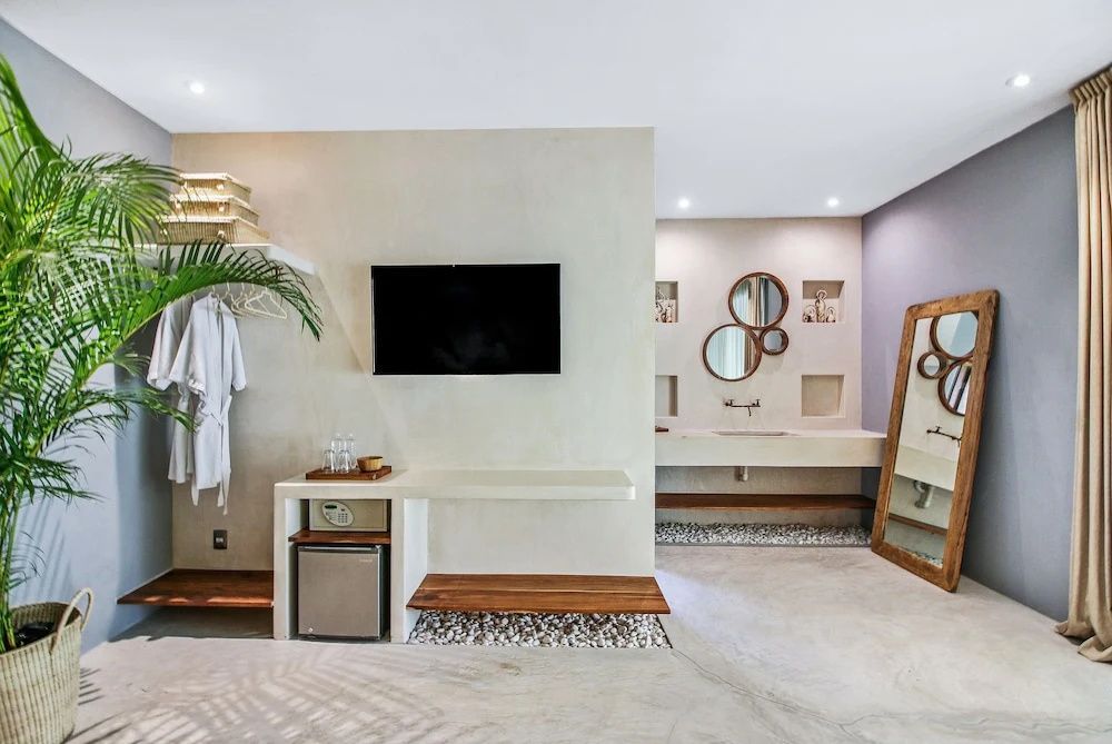 Hotelzimmer mit Minibar, Fernseher, Bademantel und angrenzendem Waschbereich.