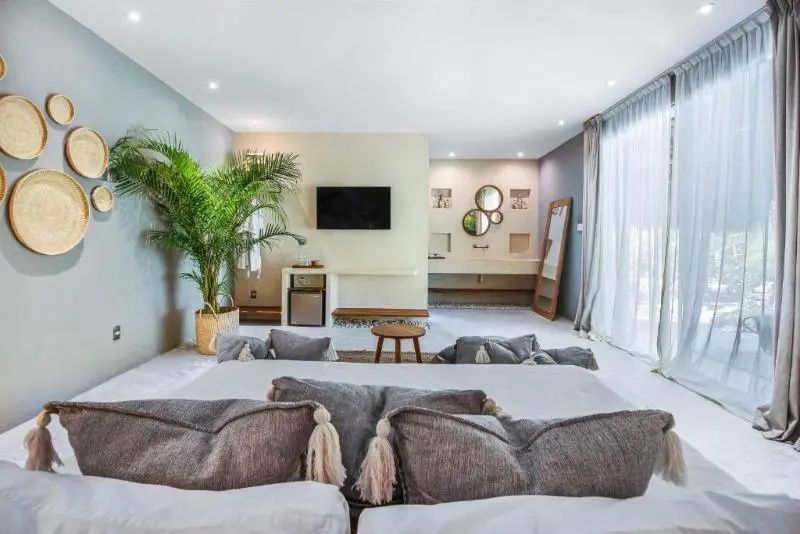 Blick vom Bett auf einen Fernseher und den offenen Badezimmerbereich im Hintergrund.