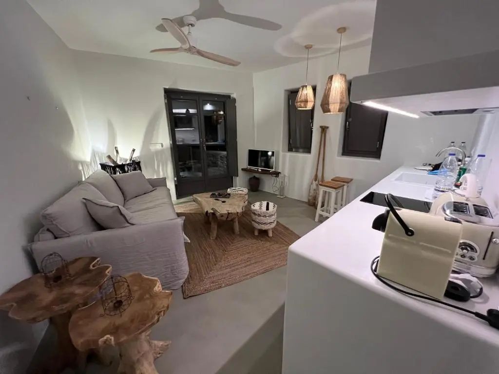 Wohnbereich der Suite mit hellem Sofa, Holztisch und einer Küchenzeile.