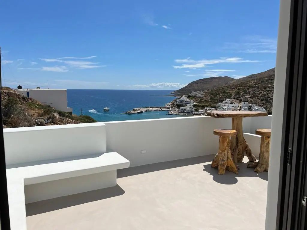 Sonnige Terrasse mit Holzmöbeln und Blick auf das Meer und die Bucht.