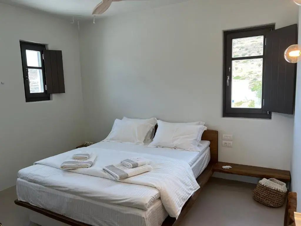 Helles Schlafzimmer mit weiß bezogenem Doppelbett und Holzrahmen.