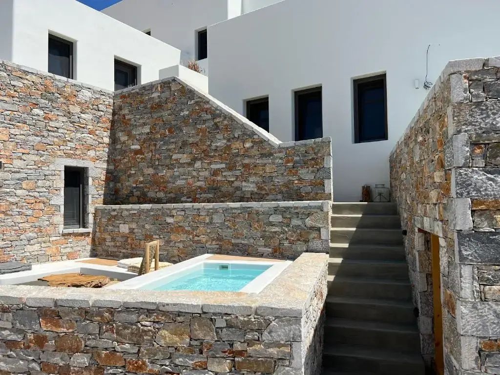 Außenbereich der Anlage mit Steinmauern, weißer Fassade und kleinem Pool.