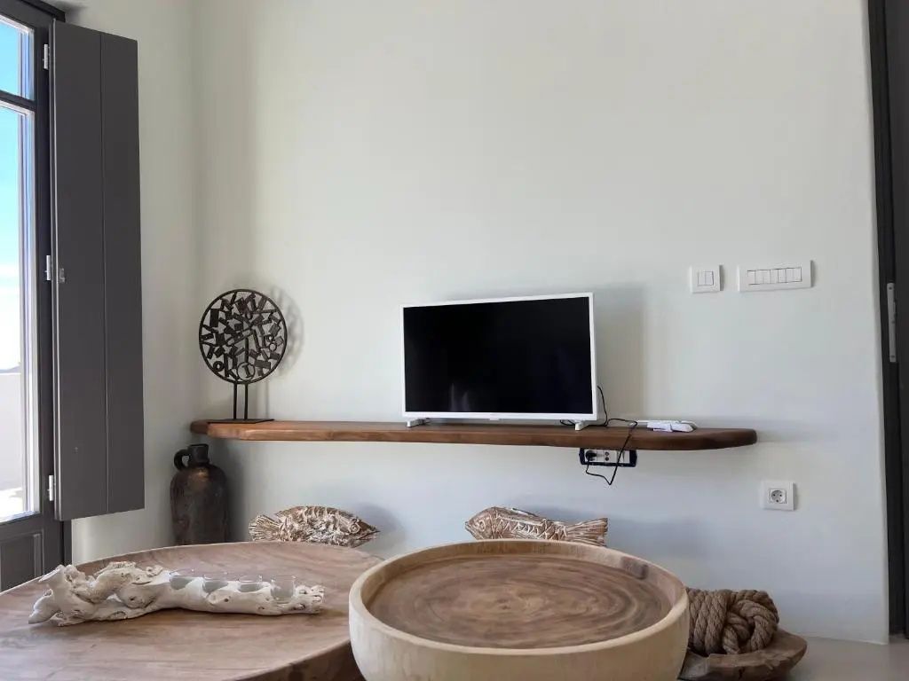 Fernseher auf einem Wandregal aus Holz über einem Holztisch.