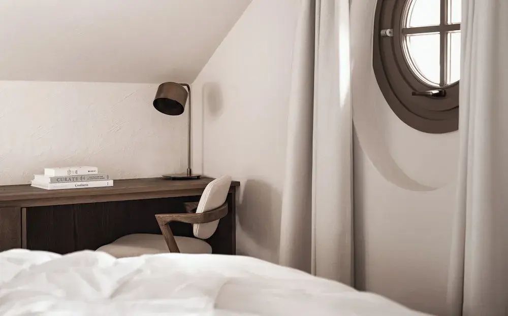 Schreibtisch mit Stuhl und Stehlampe in einer Zimmernische mit rundem Fenster.