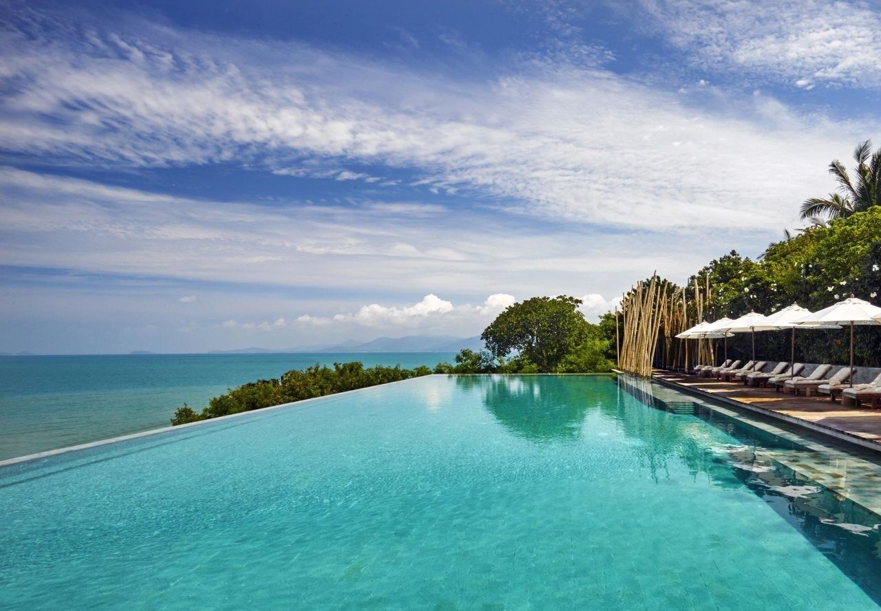 Langer Infinity-Pool mit Sonnenliegen über dem Meer im Six Senses Samui