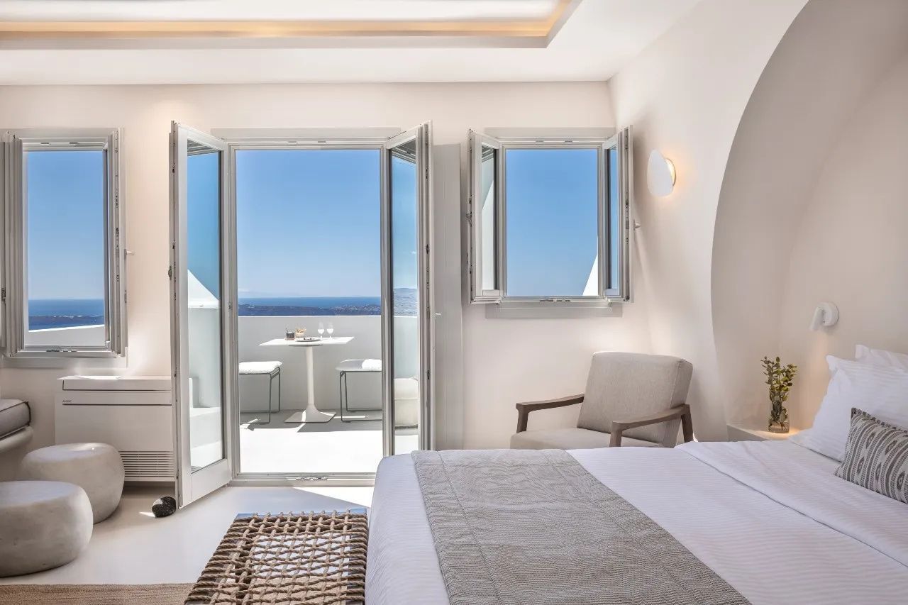 Blick vom Schlafzimmer durch geöffnete Balkontüren auf das Meer und die Terrasse.