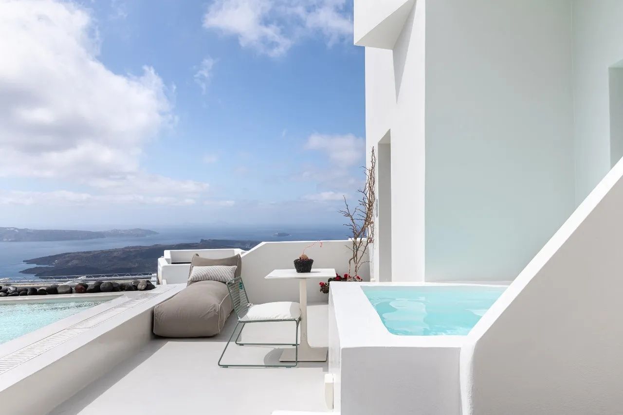 Terrasse mit Whirlpool, Liegestuhl und Weitblick auf das Meer unter blauem Himmel