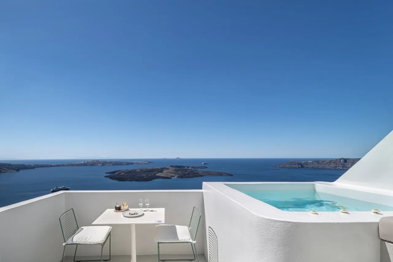Weißer Whirlpool und gedeckter Tisch auf einer Terrasse mit freiem Blick auf das Meer und Inseln.