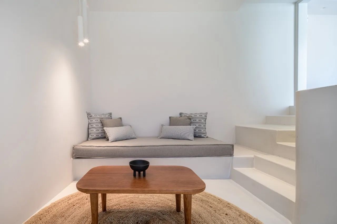 Sitzbereich mit Polsterbank, Holztisch und einer angrenzenden weißen Treppe in der Suite.