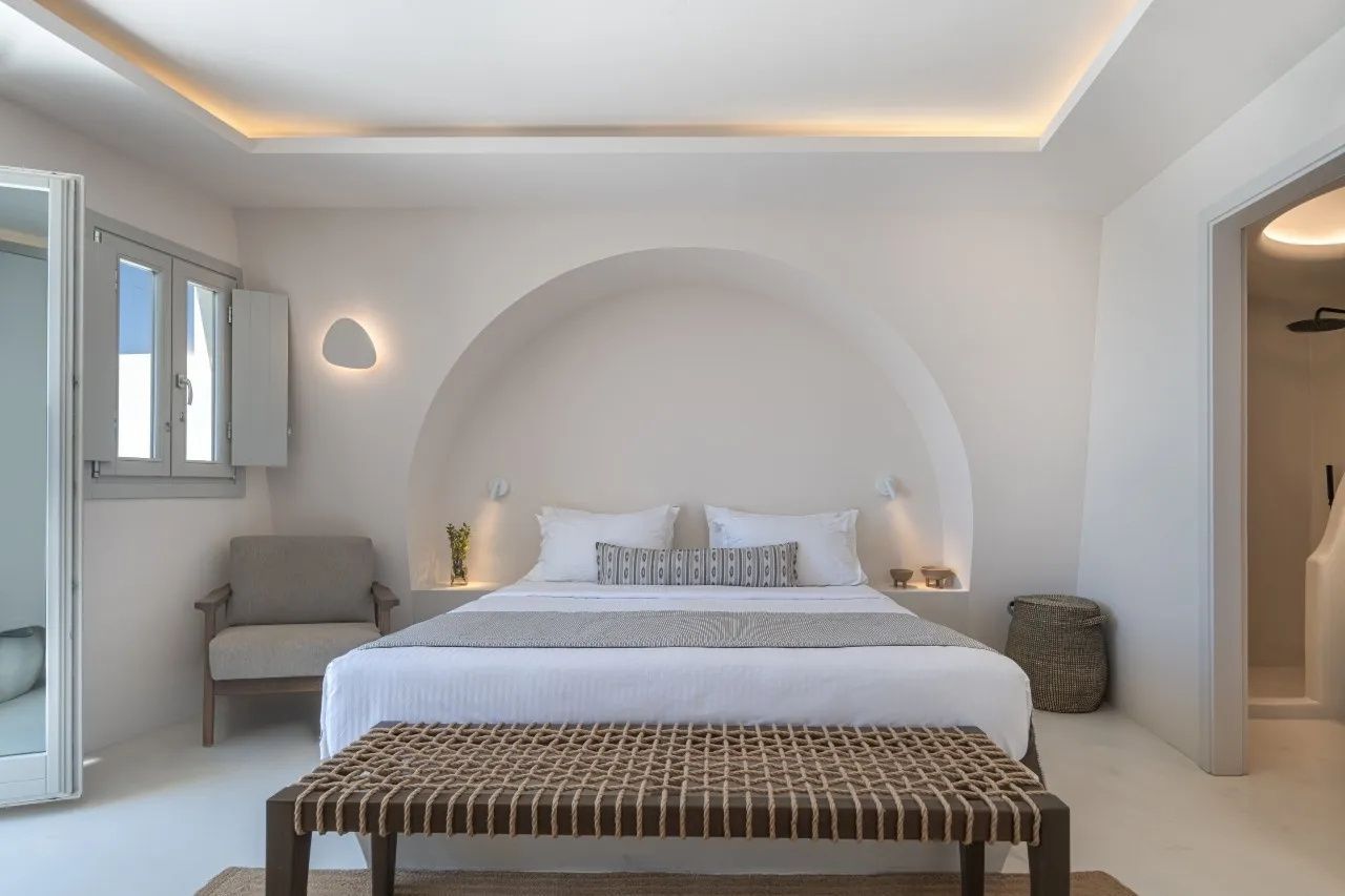 Helles Schlafzimmer mit weiß eingefasstem Doppelbett in einer Rundbogennische.