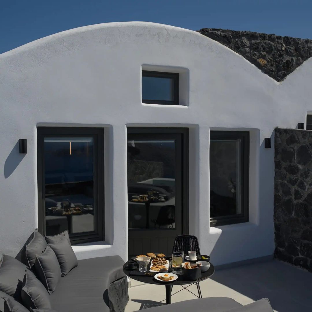 Weiße Fassade einer Suite mit eigener Terrasse, Sitzmöbeln und einem gedeckten Tisch.