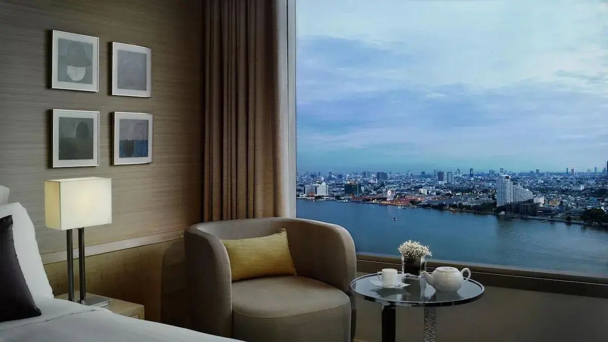 Sessel am bodentiefen Fenster mit Blick auf den Fluss Chao Phraya und die Stadt.