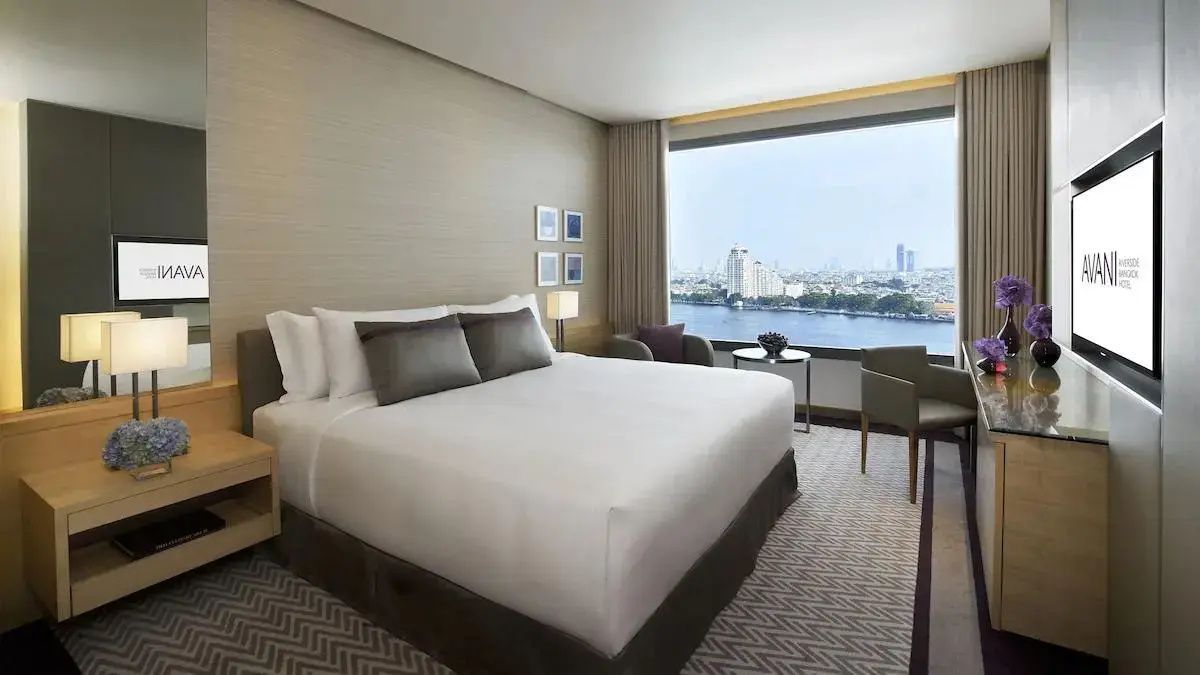 Hotelzimmer mit Doppelbett und großem Panoramafenster mit Blick auf den Fluss und die Stadt