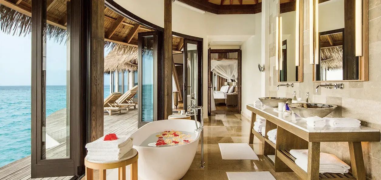 Freistehende Badewanne mit Blütenblättern in einem hellen Badezimmer nahe der Terrasse.
