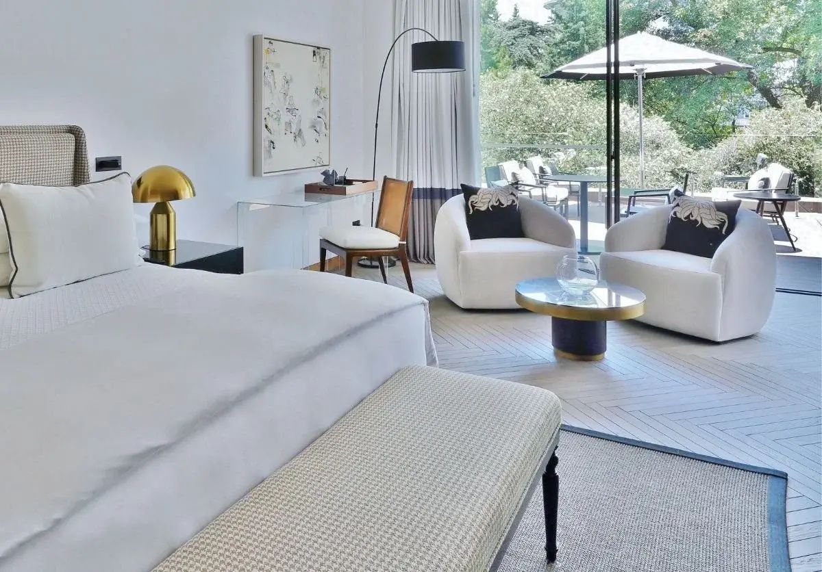 Moderner Wohnbereich im Zimmer mit zwei Sesseln, Tisch und Zugang zur Terrasse.