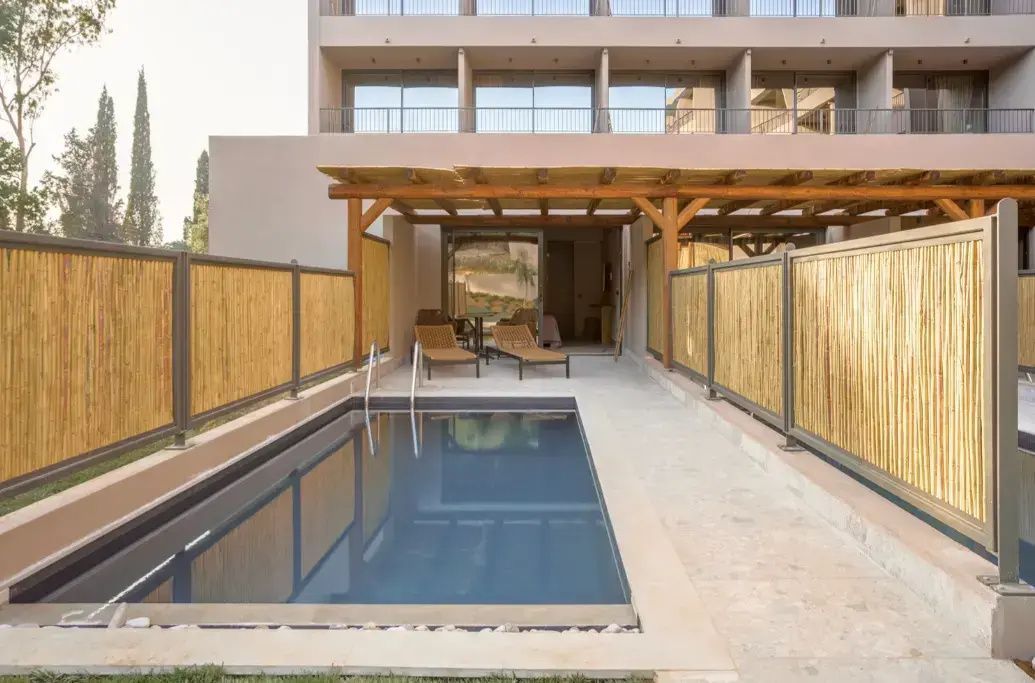 Privater Pool auf der Terrasse einer Erdgeschoss-Suite mit Sonnenliegen unter Holzüberdachung.