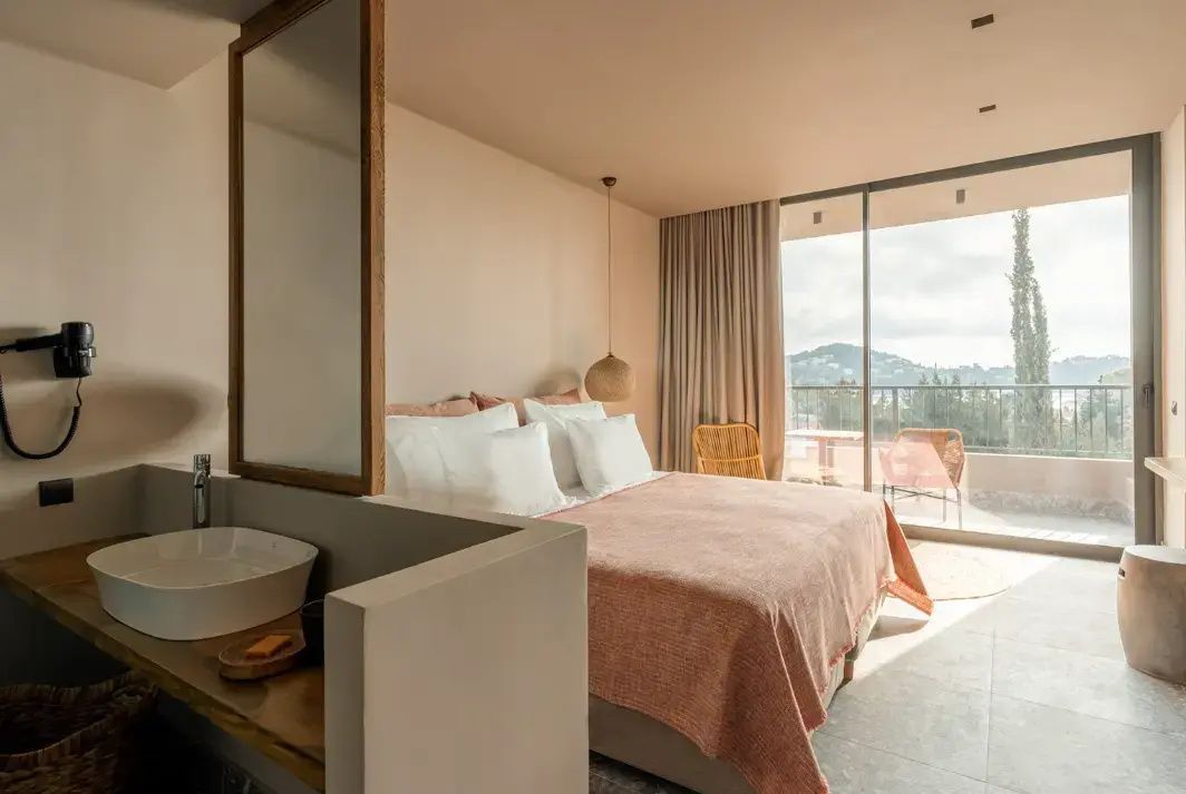 Hell eingerichtetes Doppelzimmer mit Balkonzugang und Blick ins Grüne.