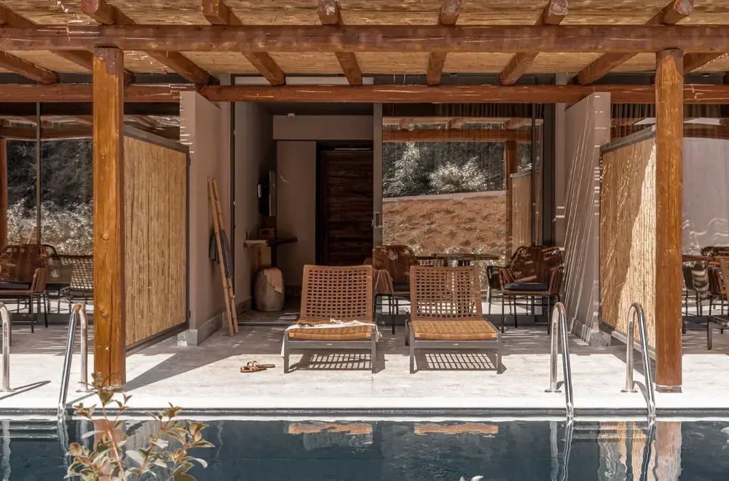 Außenansicht einer Terrasse mit Holzüberdachung, Liegestühlen und eigenem Pool.