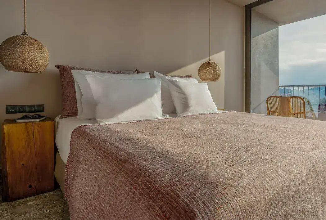 Doppelbett mit rosa Tagesdecke und weichen Kissen im Hotelzimmer