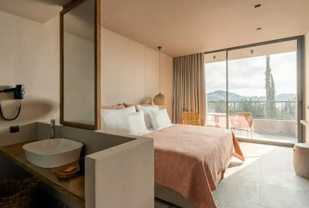 Hell eingerichtetes Hotelzimmer mit Doppelbett und integriertem Waschbecken