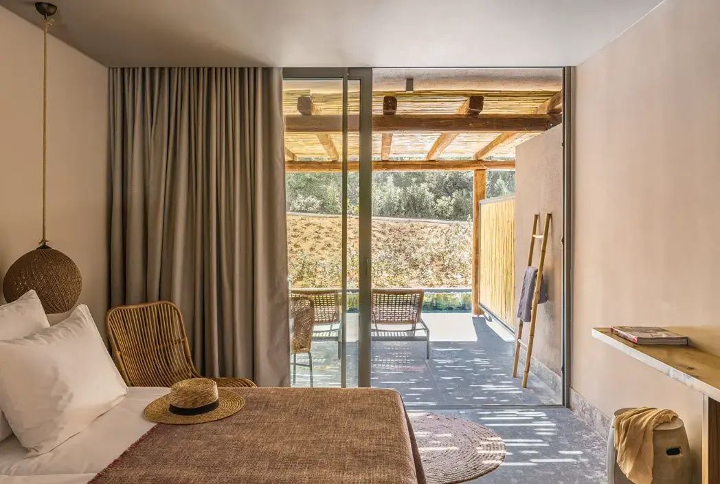 Ein Hotelzimmer mit Bett und Stuhl bietet durch eine Glastür Blick auf die Terrasse.
