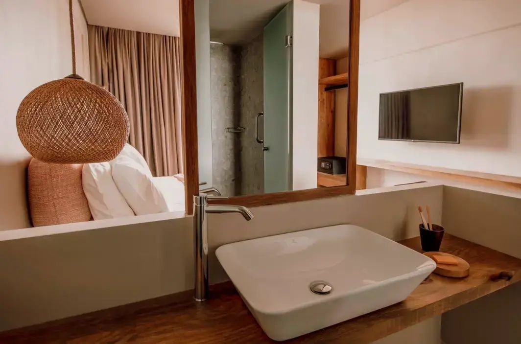 Weißes Waschbecken auf einer Holzablage mit einem Spiegel im Hotelbadezimmer.