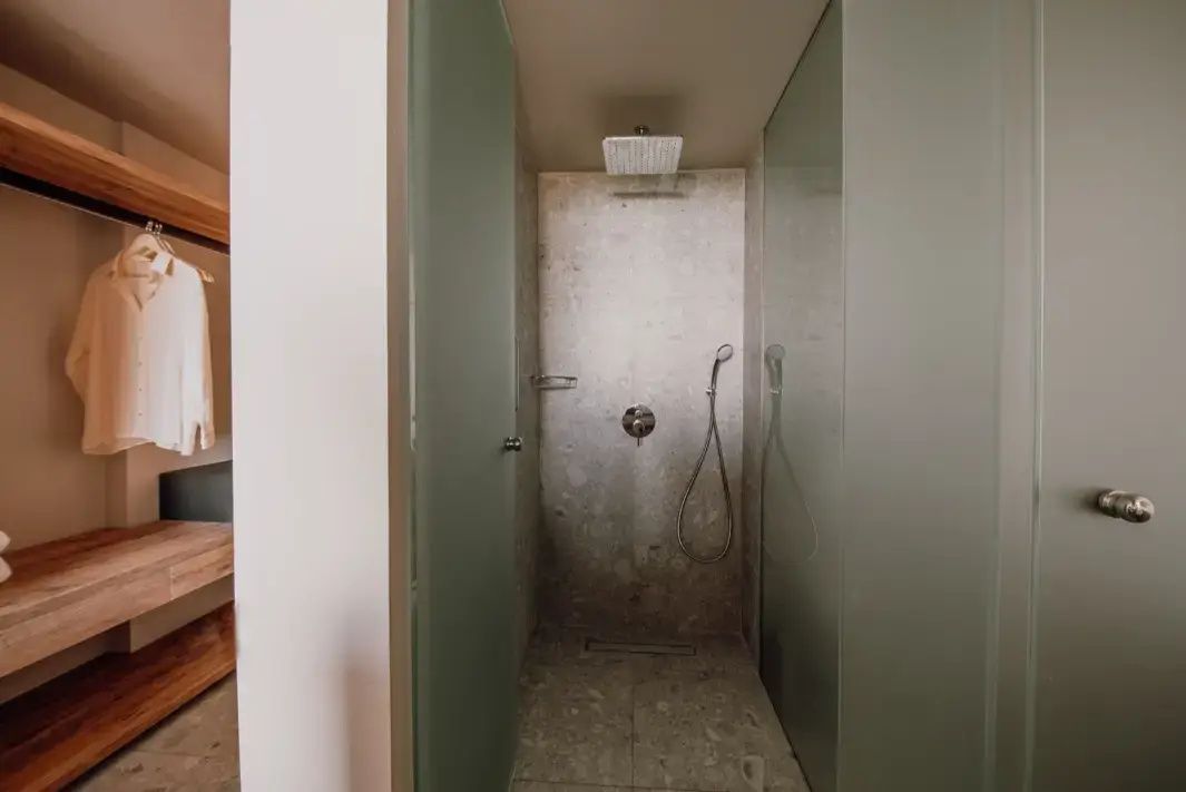 Ebenerdige Dusche mit Regenduschkopf und Wänden aus Naturstein im Badezimmer.