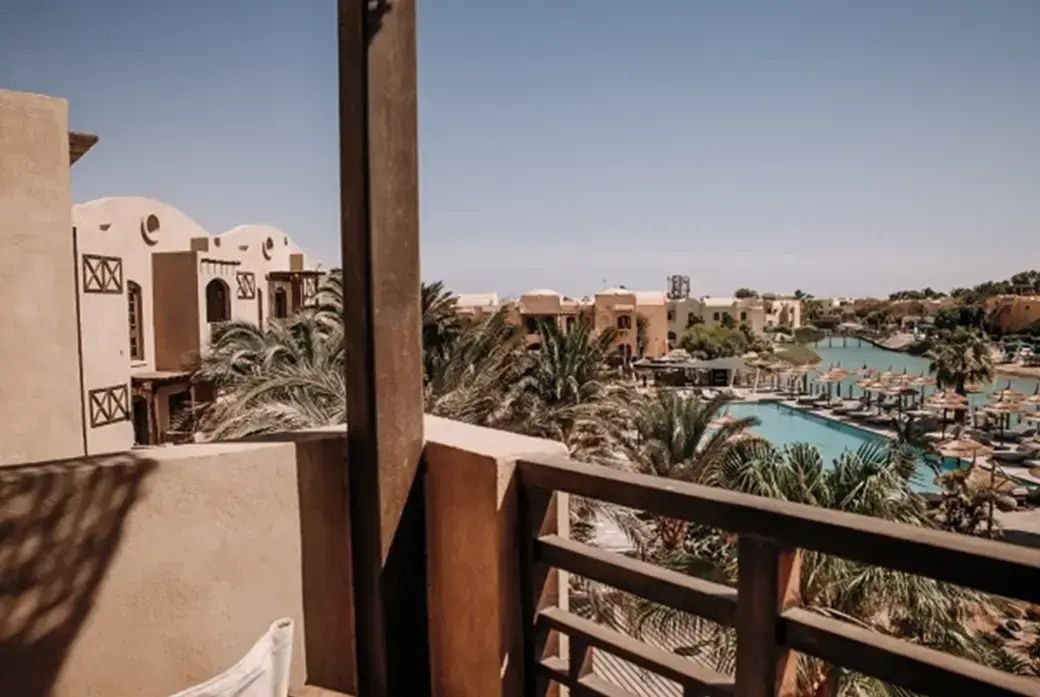 Blick vom Balkon auf Palmen, den Swimmingpool, die Hotelanlage und die Lagune.