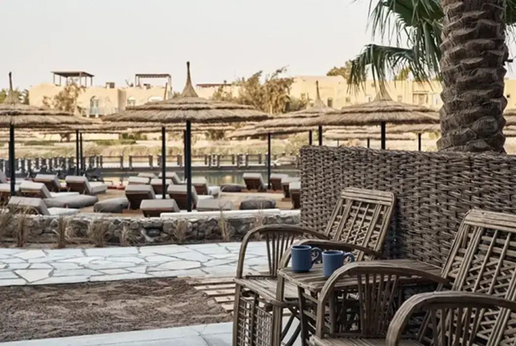 Sitzgelegenheit auf einer Terrasse mit Blick auf den Strand und Sonnenschirme.
