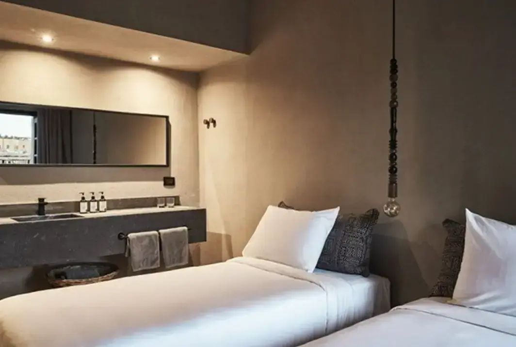 Einbettzimmer im minimalistischen Stil mit beigen Wänden und offen integriertem Waschtisch.