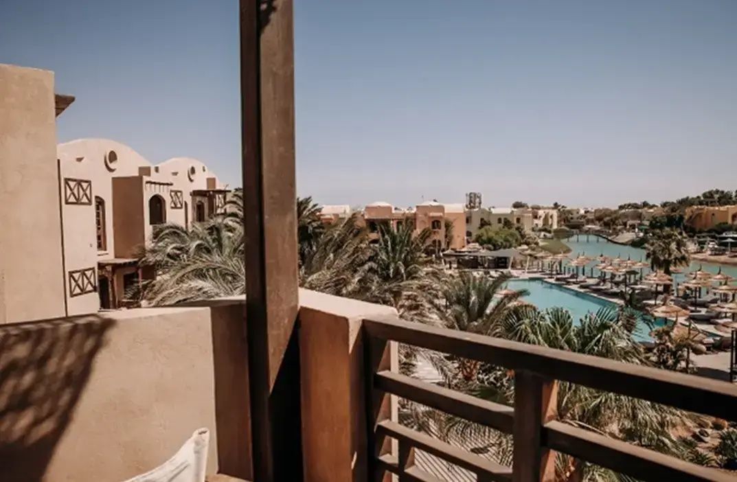 Blick vom Balkon auf den Poolbereich, Palmen und die orientalische Anlage.