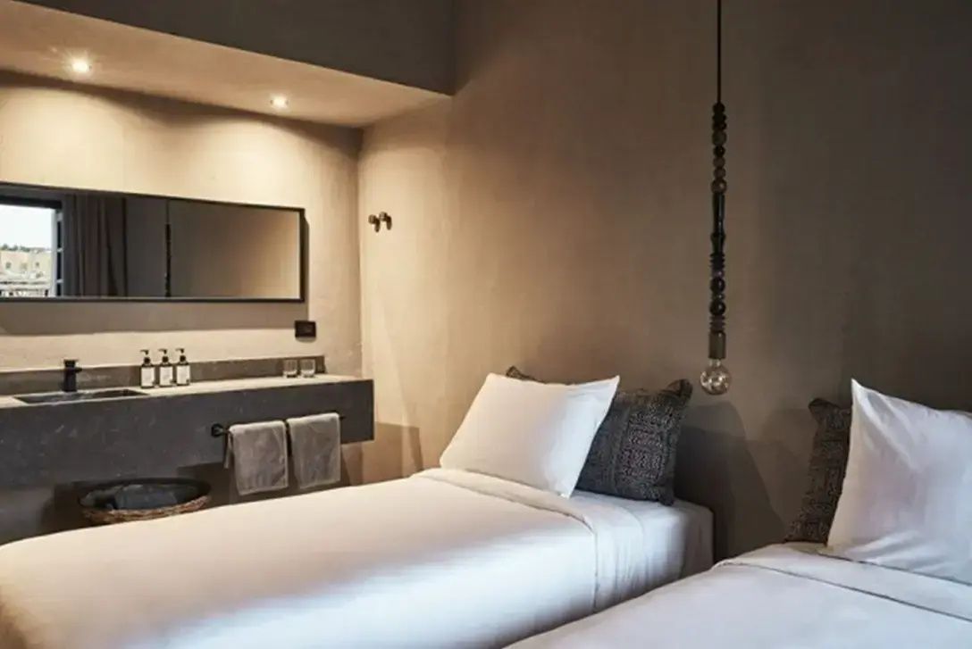 Hotelzimmer im schlichten Stil mit Betten und integriertem Waschtisch an der Wand.