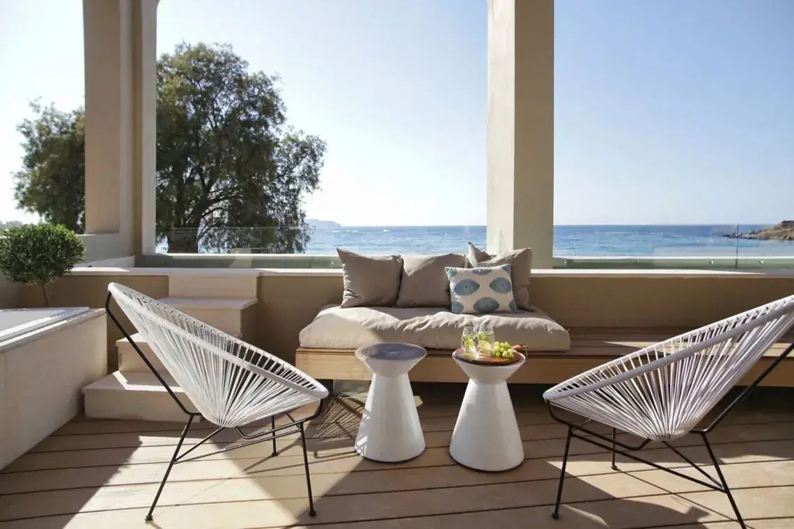 Überdachte Terrasse mit Lounge Möbeln, Sitzstühlen und freiem Blick auf das Meer.