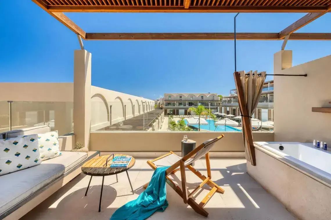 Dachterrasse mit Liegestuhl, Holzüberdachung und Ausblick auf die Außenpools des Hotels.