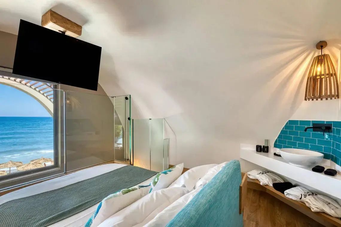 Hotelzimmer mit gewölbter Decke, großem Bett, Fernseher und offenem Badezimmerbereich.