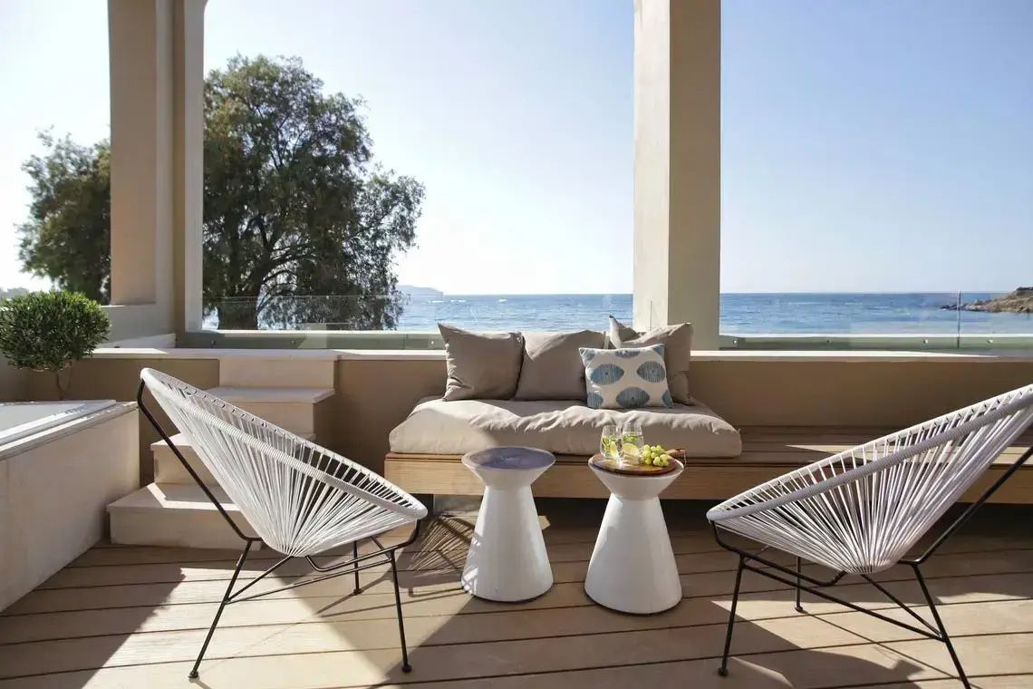 Überdachte Terrasse mit Sitzmöbeln und direktem Blick auf das blaue Meer.