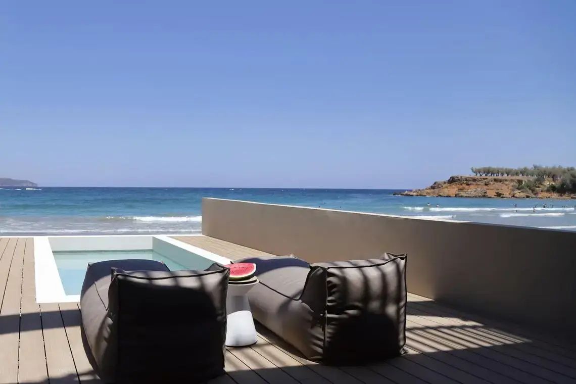 Sonnendeck mit zwei großen Sitzkissen, Beistelltisch und freiem Blick auf das türkisfarbene Meer.